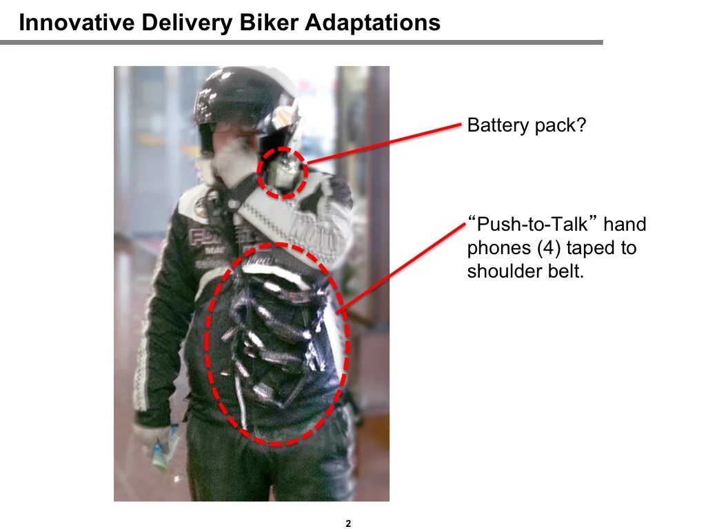 Field observation of a delivery biker: four push-to-talk handsets taped to shoulder belt and a battery pack, illustrating how workers improvise tools when no designed solution exists.